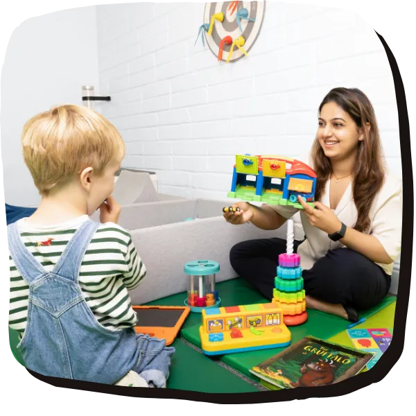 A child client and psychologist play together - she is facing the camera and he has his back to the camera