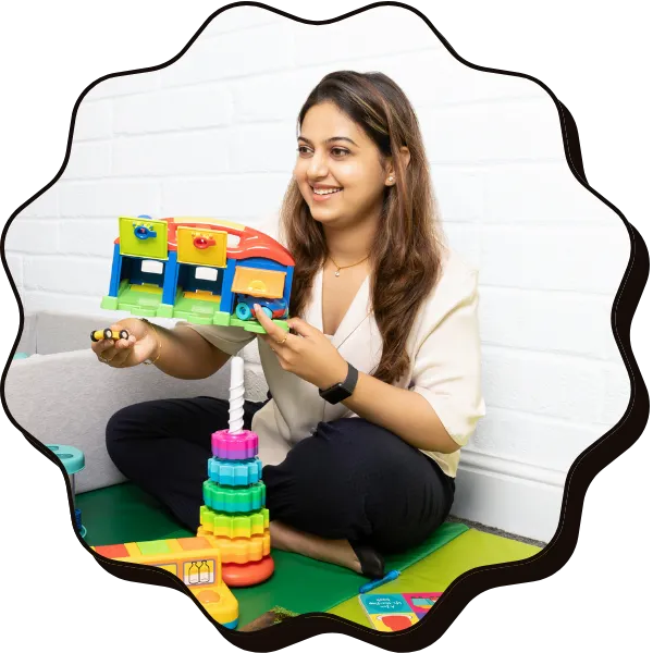 An Asian woman holding a childrens toy bus smiles, looking to the left of the camera