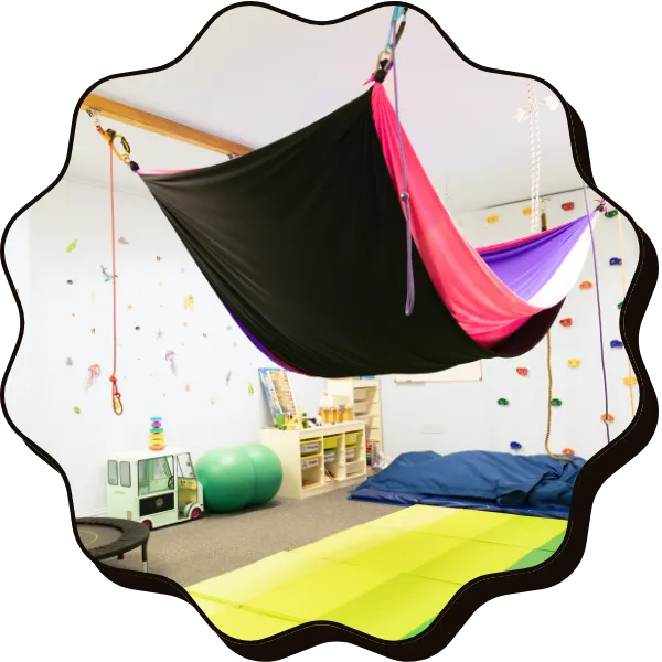 A play room with mats on the floor and a big pink hammock